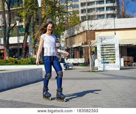 Beautiful and happy Roller Girl skating in the park. She is smiling