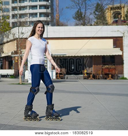 Beautiful and happy Roller Girl skating in the park. She looks down and smiles.