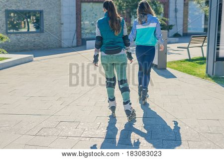 Two girls rollers go one after another. Back view