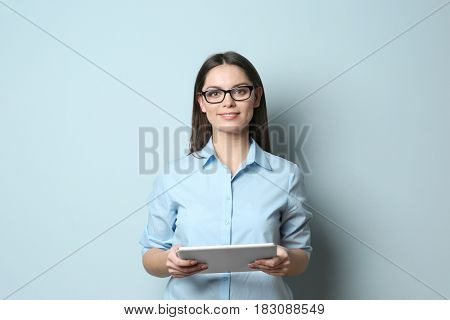 Young beautiful woman with tablet on light background