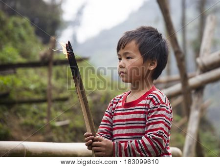 Sa Pa, Vietnam - 12 March, 2017: Ethnic minority, Hmong boy playing with the fire in tradition village of Cat cat, Sapa, Vietnam