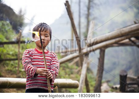 Sa Pa, Vietnam - 12 March, 2017: Ethnic minority, Hmong boy playing with the fire in tradition village of Cat cat, Sapa, Vietnam