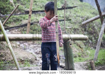 Sa Pa, Vietnam - 12 March, 2017: Ethnic minority, Hmong boy playing with the fire in tradition village of Cat cat, Sapa, Vietnam