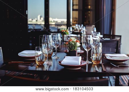 Dark table set with tableware and glassware for reception in restaurant.
