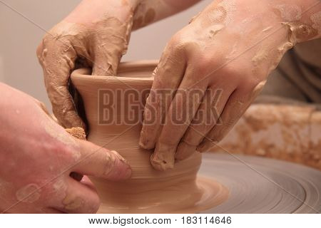 hands of a potter, creating an earthen jar on a pottery wheel