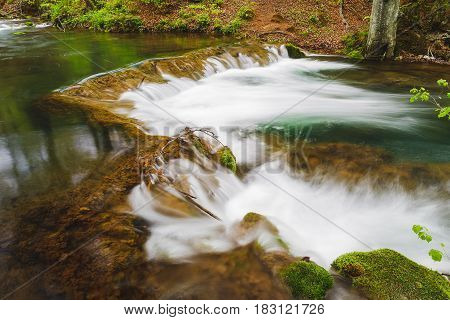 Mountain river  with mossy rocks. Long exposure of white water rapids and waves with rocks and moss. Grza river, Serbia