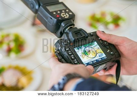 Close up male hands holding professioanl camera with a picture of food