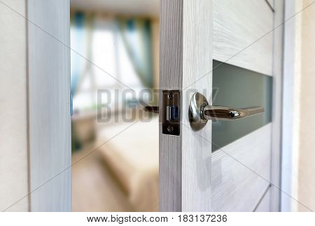 Close-up elements of the interior of the apartment. Ajar white door. Chrome door handle.