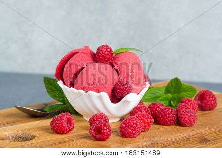 Raspberry ice cream sorbet in white bowl with spoon raspberry mint leaves copy space