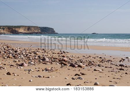 Sandy beach with lots of pebbles and stones at Martinhal in Portugal in winter