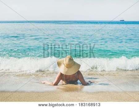 Beautiful slim senior woman tourist in bikini and hat lying on sand enjoying sea at Meditteranean resort of Turkey in Alanya, Kleopatra beach
