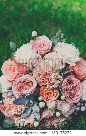 Wedding background vertical. Bouquet from rose flowers on grass. Bridal floral decoration detail outdoors in summer park, copy space