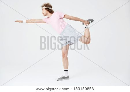 Side shot of man doing horizontal position on one leg with right hand up