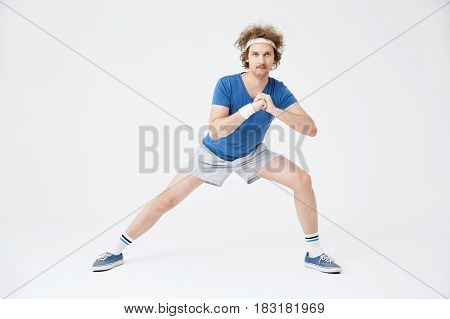 Sporty retro guy in old fashioned sport suit doing stretching exercises. Isolated on white background