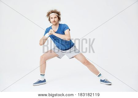 Deep side lunge position. Retro man in old style clothes warming up left leg muscles