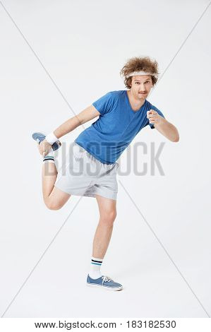 Guy stretching leg holding foot with right hand pointing at camera with pointer finger