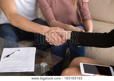 Close-up of man shaking hands with female banker after signing loan contract, health care insurance agreement, couple making deal on a matter of employment, advisory and consulting, tourist services