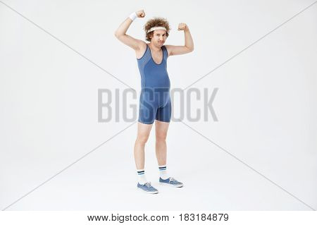 Weak man with belly showing muscles, posing in sport jumpsuit. Isolated on white background
