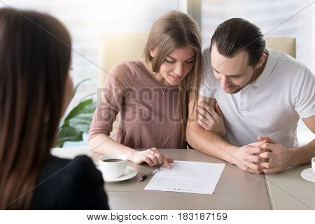 Smiling family couple reading contractual terms before signing contract, examining documents to make decision about mortgage, considering investment in property, calculating total loan liabilities