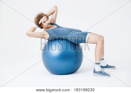 Guy in blue jumpsuit working on belly muscles looking straight. Stomach training concept. Retro style