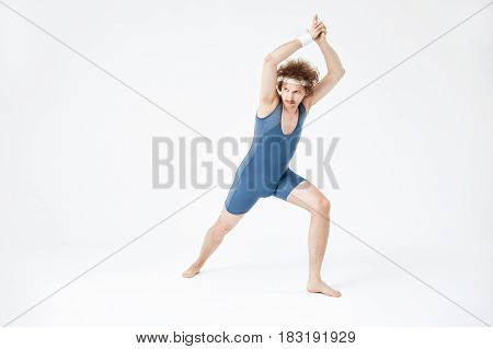 Sporty man in retro clothing doing yoga, looking away. Sport and health concept. White background