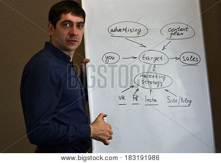 Executive man writing scheme on a flipchart