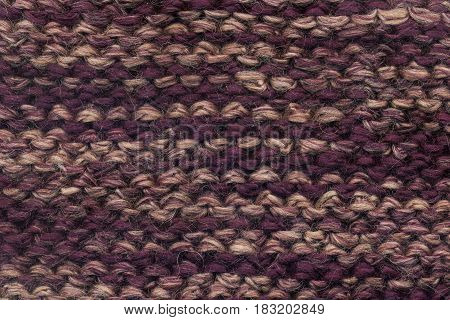 Abstract knitted purple background texture. Textile pattern of purple woolen handmade cloth. Macro of back loop wool winter fabric with geometric color ornament