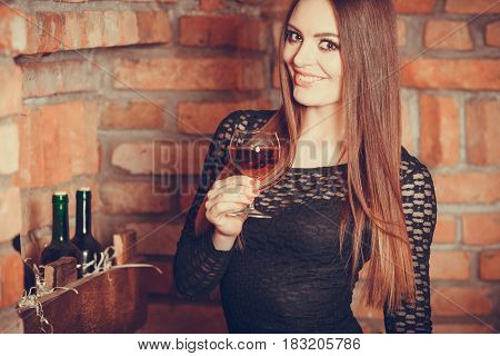Elegant beauty lady long hair full make up wearing black dress tasting wine in rural cottage interior celler
