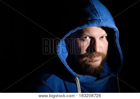 Solid bearded middle-aged man in a hood  portrait on black background
