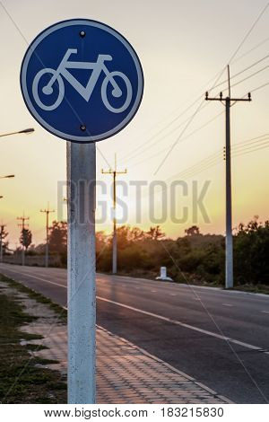 Round bicycle lane sign on sunset background.
