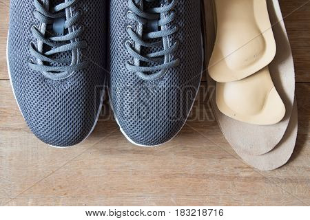 Gray sport shoes with orthopedic insoles. Wooden background.