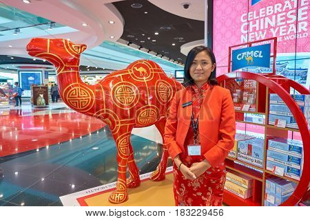 DUBAI, UAE - CIRCA JANUARY, 2017: indoor portrait of promouter in red asian style clothing at Dubai International Airport. The airport is home to the long-haul carrier Emirates.