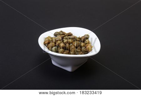 bowl with fresh capers isolated on black background