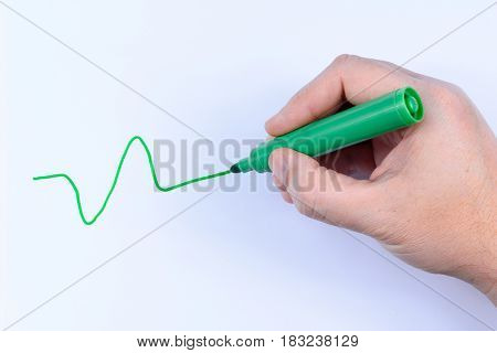 Hand holding a green pen drawing a wavey line isolated on white background