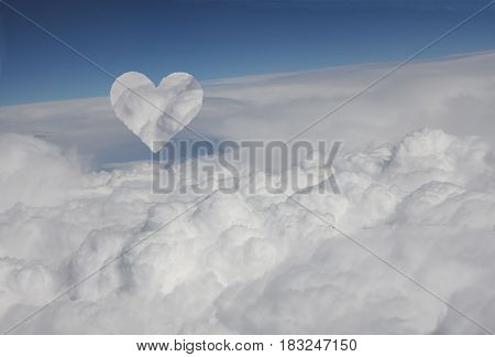 Cloud heart arising from blanket of clouds under blue sky