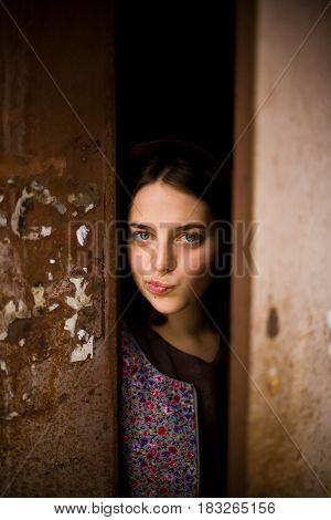 A Young Curious Girl Looks Out From Behind The Door Of Her House. She Thinks About Going Outside. Ag