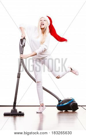 Woman vacuuming the house. Funny teen girl in santa helper hat with vacuum cleaner. Christmas time and housework concept.
