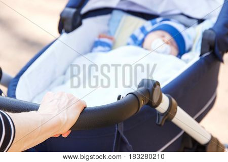 Hand Of Woman Holding Babies Pram With Newborn Baby Sleeping Inside