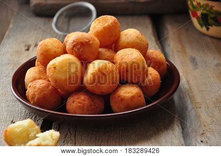 Small balls of freshly baked homemade cottage cheese doughnuts in a plate on a wooden background. Rustic style.