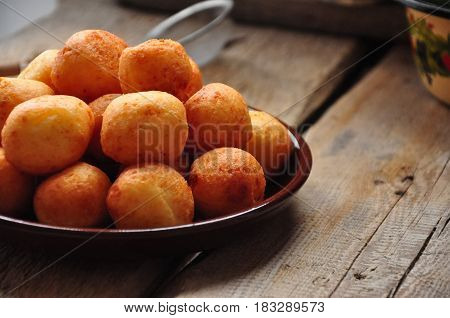 Small balls of freshly baked homemade cottage cheese doughnuts in a plate on a wooden background. Rustic style.