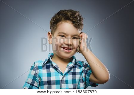 Portrait of happy boy with mobile going surprise on gray background.