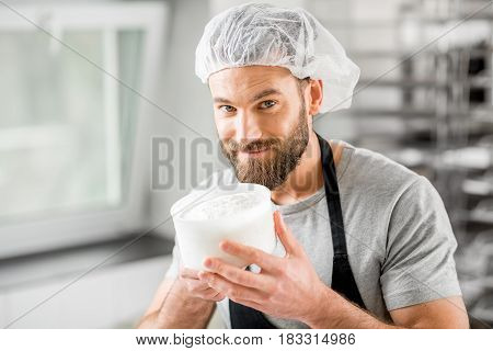Handsome man in uniform enjoying the process of making cheese at the small producing farm
