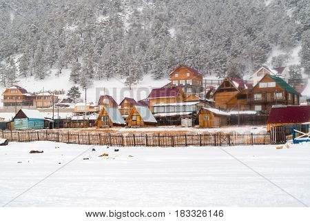 View of Goloustnoye Village in the winter with snowslide at the mountain