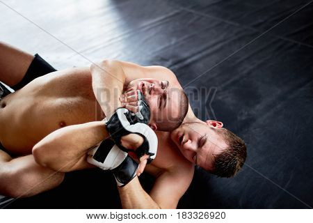 Portrait of shirtless professional  wrestlers fighting in boxing ring: throwing opponent on floor and performing headlock