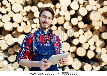 Happy young lumber with touchpad working on lumberyard