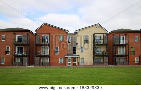Bracknell, England - April 12, 2017: View of the exterior of a modern apartment block with balconies and a green space in front on a cloudy day in Bracknell, England