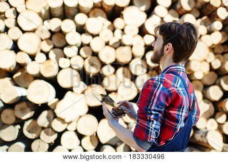 Forester with touchpad looking at stack of logs
