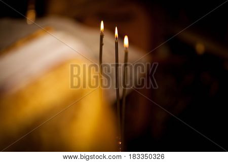 three church candles on a black background