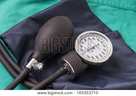 Blood pressure device located on the hospital green background. The background can be a textile part of a doctor or nurse's work uniform