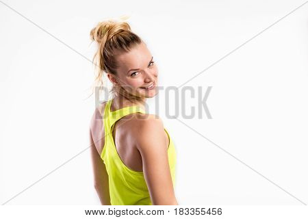 Attractive young fitness woman in yellow tank top. Studio shot on gray background.